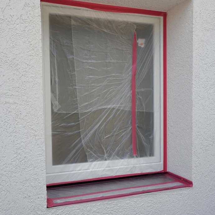 Mit Folie und Klebeband abgedecktes Fenster.