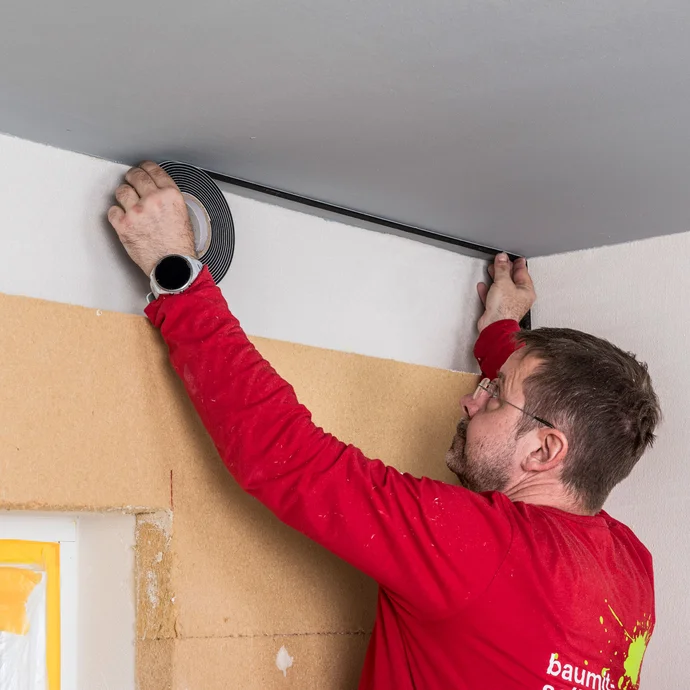 Der Heimwerker klebt vor der letzten D&auml;mmplattenreihe das Fugendichtband an der Decke an. Baumit Selbermachen Innend&auml;mmung kleben Anleitung.
