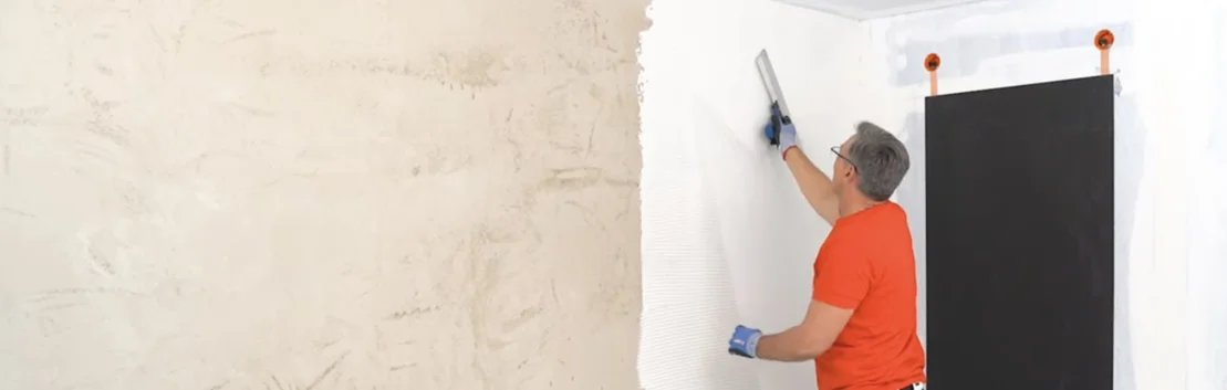 Heimwerker beim Spachteln einer Wand mit wei&szlig;er Farbe; Schritt-f&uuml;r-Schritt-Erkl&auml;rung f&uuml;r modernes Finish im Innenbereich.