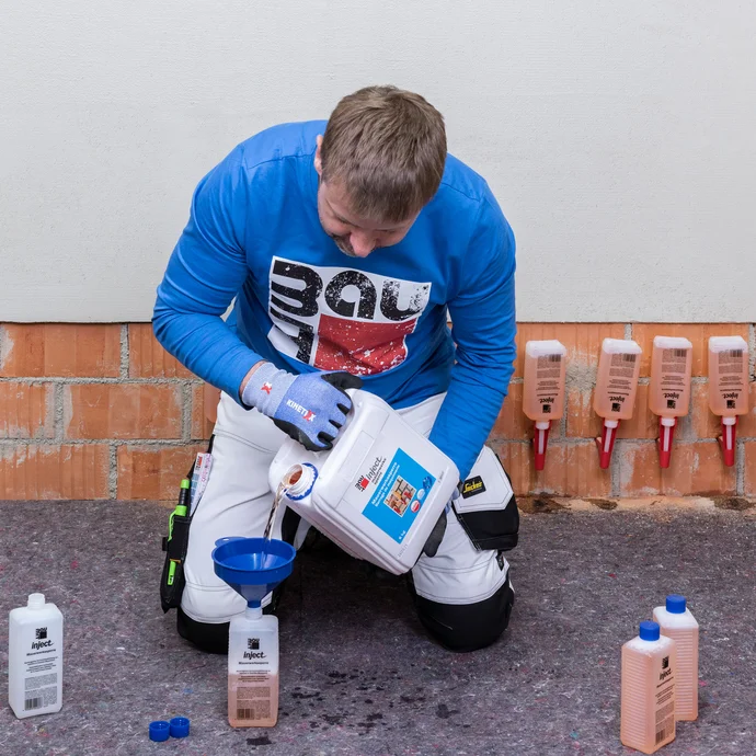 Der Handwerker f&uuml;llt die einzelnen Fl&auml;schchen der Mauerwerkssperre wieder auf.