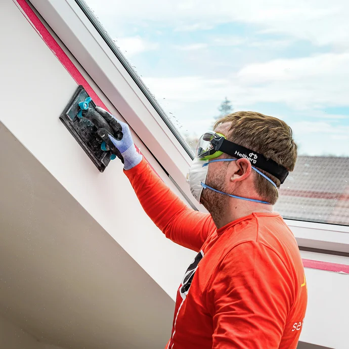 Die Laibung am Dachfenster wird mit einem Handschleifer abgeschliffen.