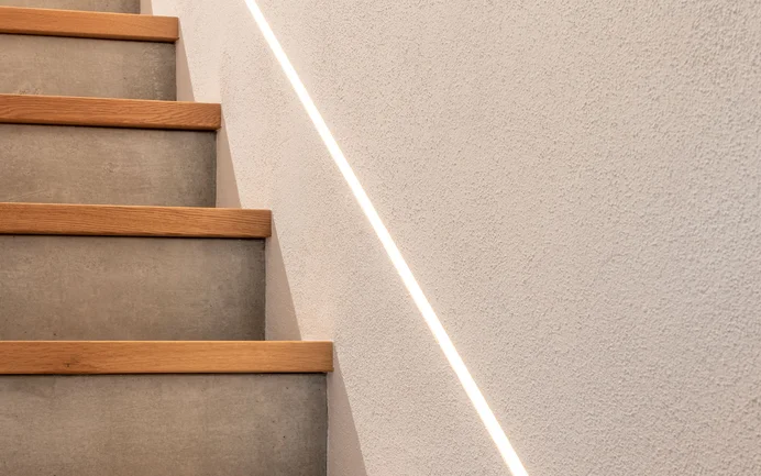 Moderne trapopgang in een eengezinswoning met beton, hout, indirecte verlichting en de stralend witte, fijne InStyle Edelwit.