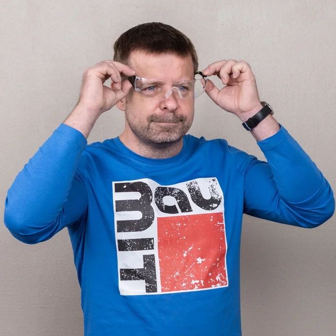 Person zieht zum Schutz eine Sicherheitsbrille auf. So ist der Heimwerker beim L&ouml;cher bohren im Ziegelmauerwerk gesch&uuml;tzt.