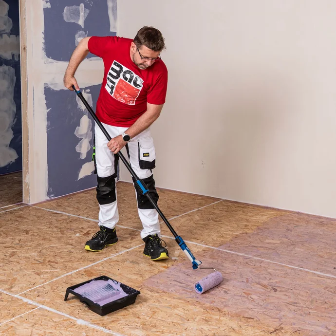 Der Baumit Handwerker grundiert den Boden aus Spanplatten mit einer passenden Grundierung - in diesem Fall mit Supergrund.