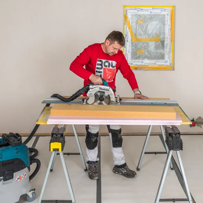 Heimwerker schneidet Baumit Holzfaserd&auml;mmplatte mit einer Handkreiss&auml;ge und F&uuml;hrungsschiene gerade zu &ndash; sauberer und gerader Zuschnitt der Innend&auml;mmung mit angeschlossenem Industriestaubsauger, Baumit Selbermachen Anleitung.