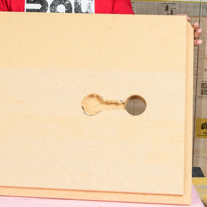 Die Holzfaserdämmplatte ist für die Gerätedose vorbereitet. Detailaufnahme der Platte mit ausgesägtem Loch für die Verteilerdose und die Ausfräsung für die Kabelführung.