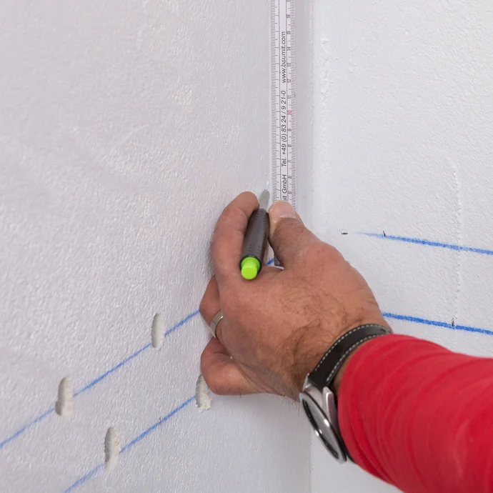 Handwerker zeichnet die dritte Bohrlochreihe 5 cm &uuml;ber der zweiten an. Die dritte Bohrlochreihe betr&auml;gt eine L&auml;nge von 15 bis 20 cm. Es wird alle 5 cm eine Markierung gesetzt.