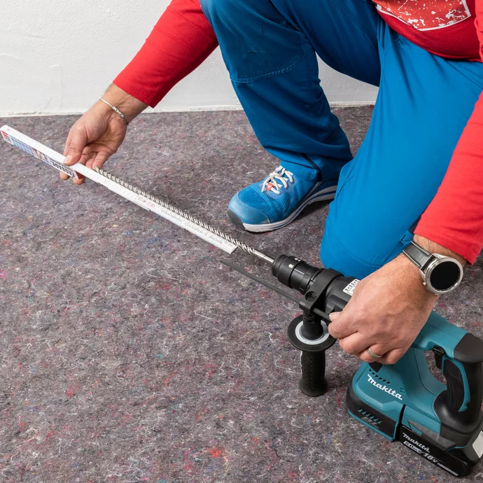 Handwerker misst die optimale L&auml;nge des Bohrers der Bohrmaschine ab.