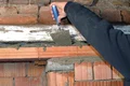 Person verspachtelt Ziegelwand mit Mörtel.