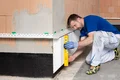 De plintisolatieplaat wordt waterpas gesteld met een waterpas.