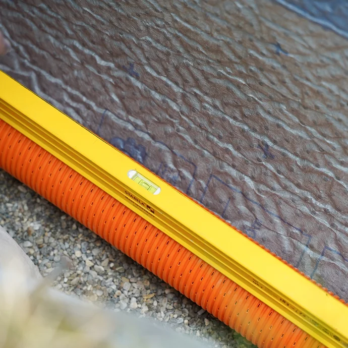 Detailaufname: Wasserwaage auf Drainagerohr.