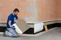 De plintisolatieplaat wordt vastgelijmd aan het metselwerk.