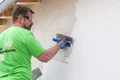 Handyman brengt de Munich roughcast op de gevel aan met een vlakspaan.