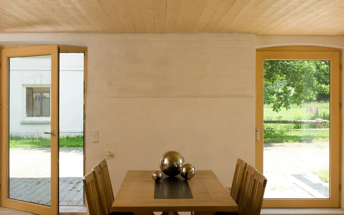 De eethoek is bepleisterd met Baumit kleipleister en geschilderd in beigetinten. Het houten plafond en de meubels geven de ruimte een warme sfeer.